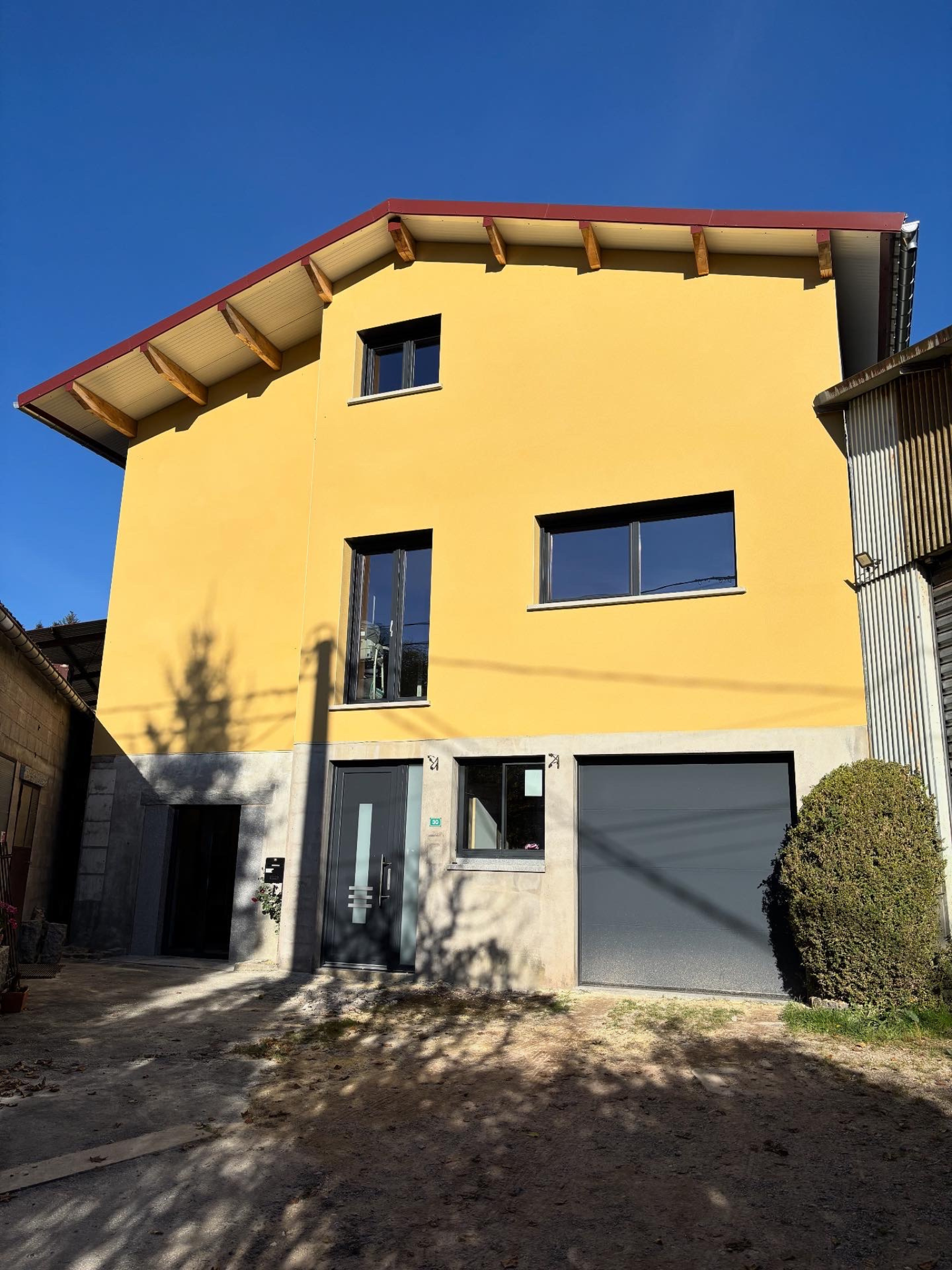 Façade de maison neuve avec sous-enduit ciment/chaux, trame en fibre de verre et enduit de finition à la chaux grattée réalisée par Les Couleurs MS.