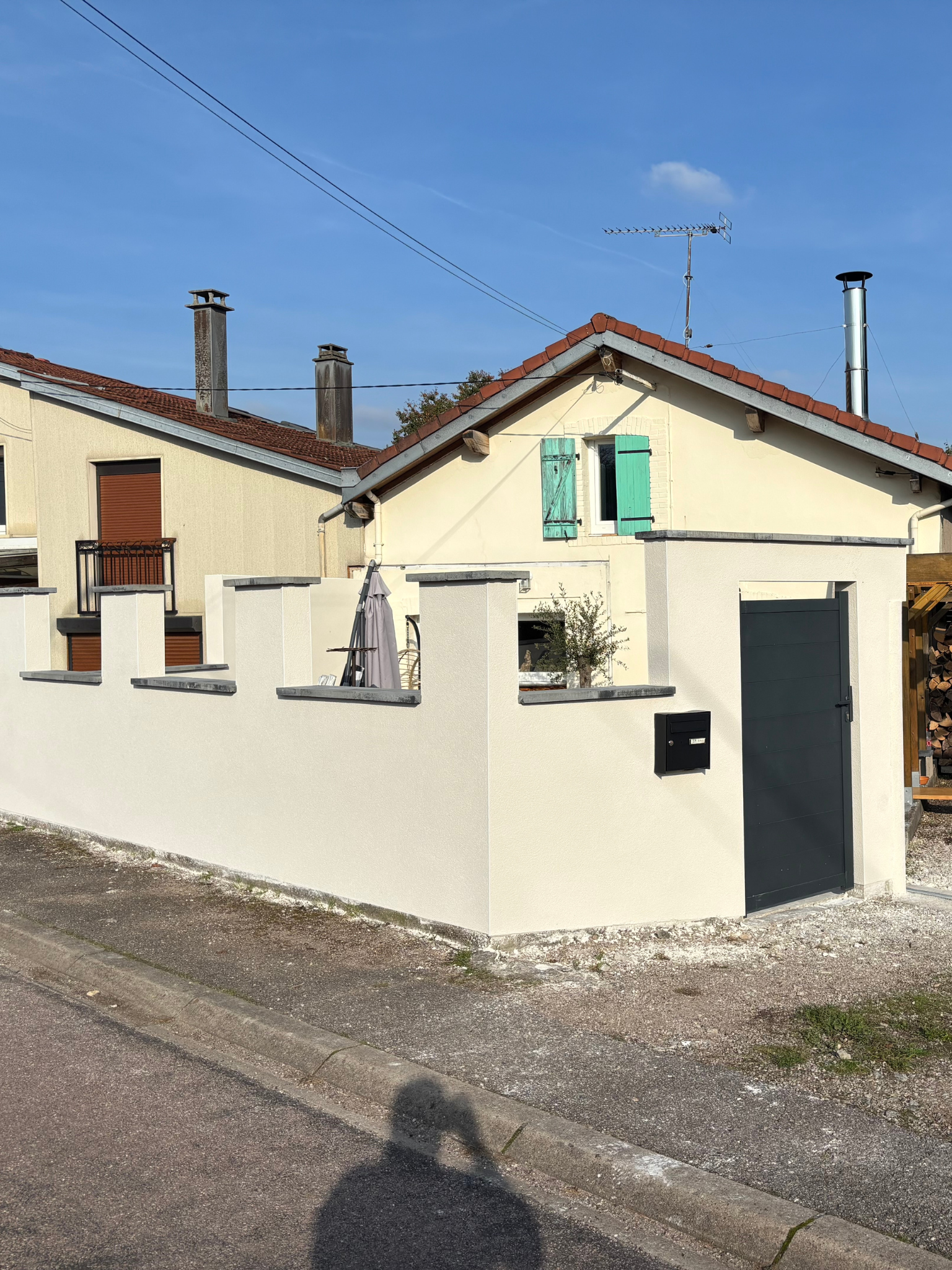 Crépi monocouche Baumit Granicem Light teinte Alger en finition grattée sur murette extérieure avec enduit RPE appliqué sur deux poteaux de portail ronds après préparation du support et pose de baguettes d'angle.
