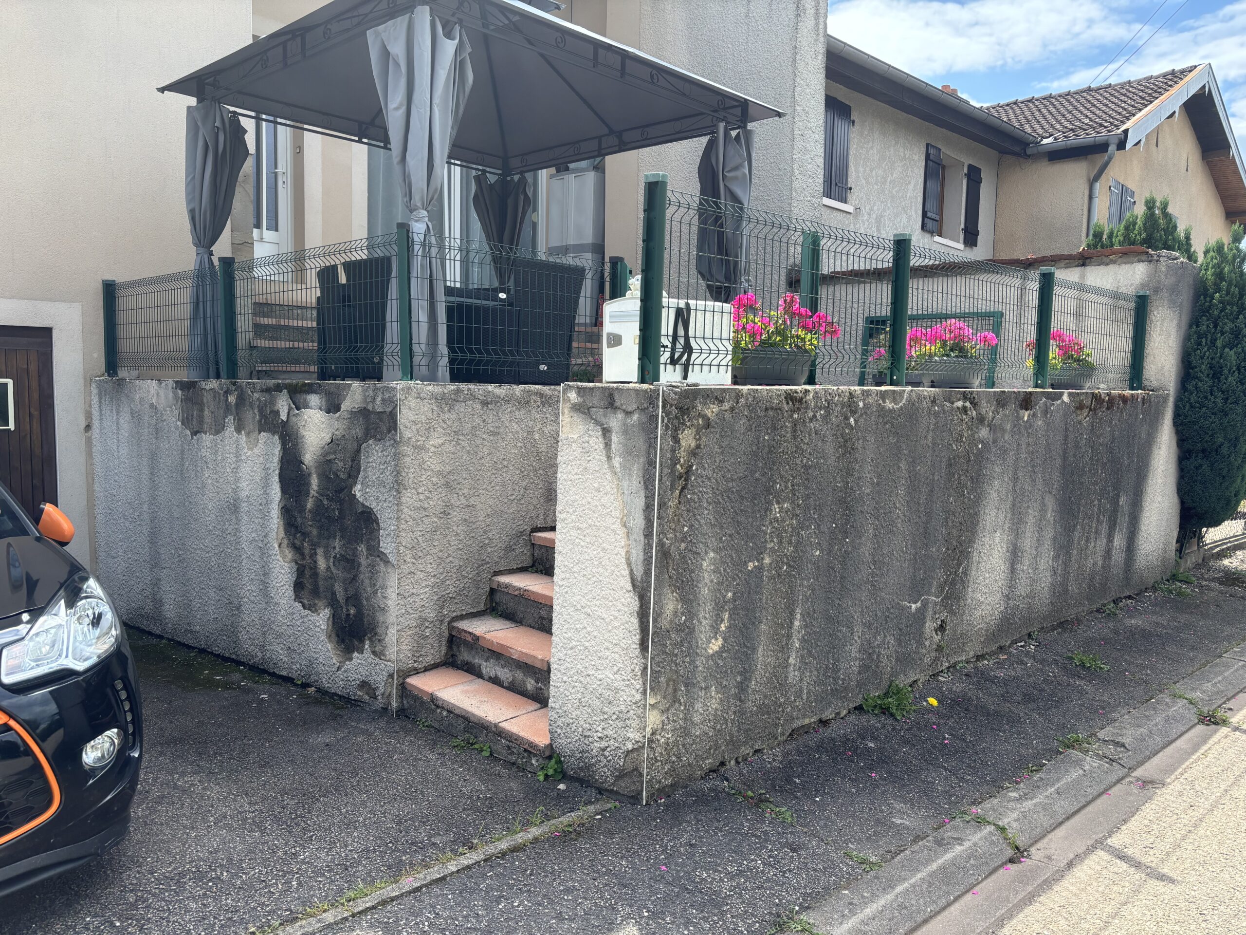 Photo de la murette avant travaux à Romont 88, montrant un support brut destiné à être rénové par l’entreprise Les Couleurs M.S. : décrépissage, nettoyage, primaire d’accrochage, enduit projeté et finition grattée.