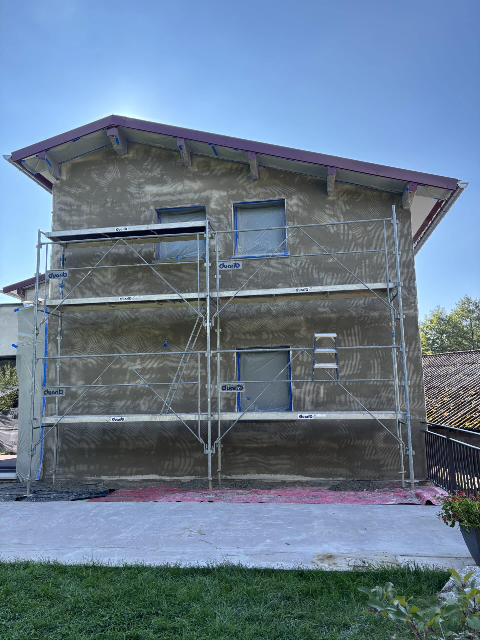 Façade de maison neuve en cours de chantier avec échafaudage, baguettes et sous-enduit ciment chaux – Les Couleurs MS.