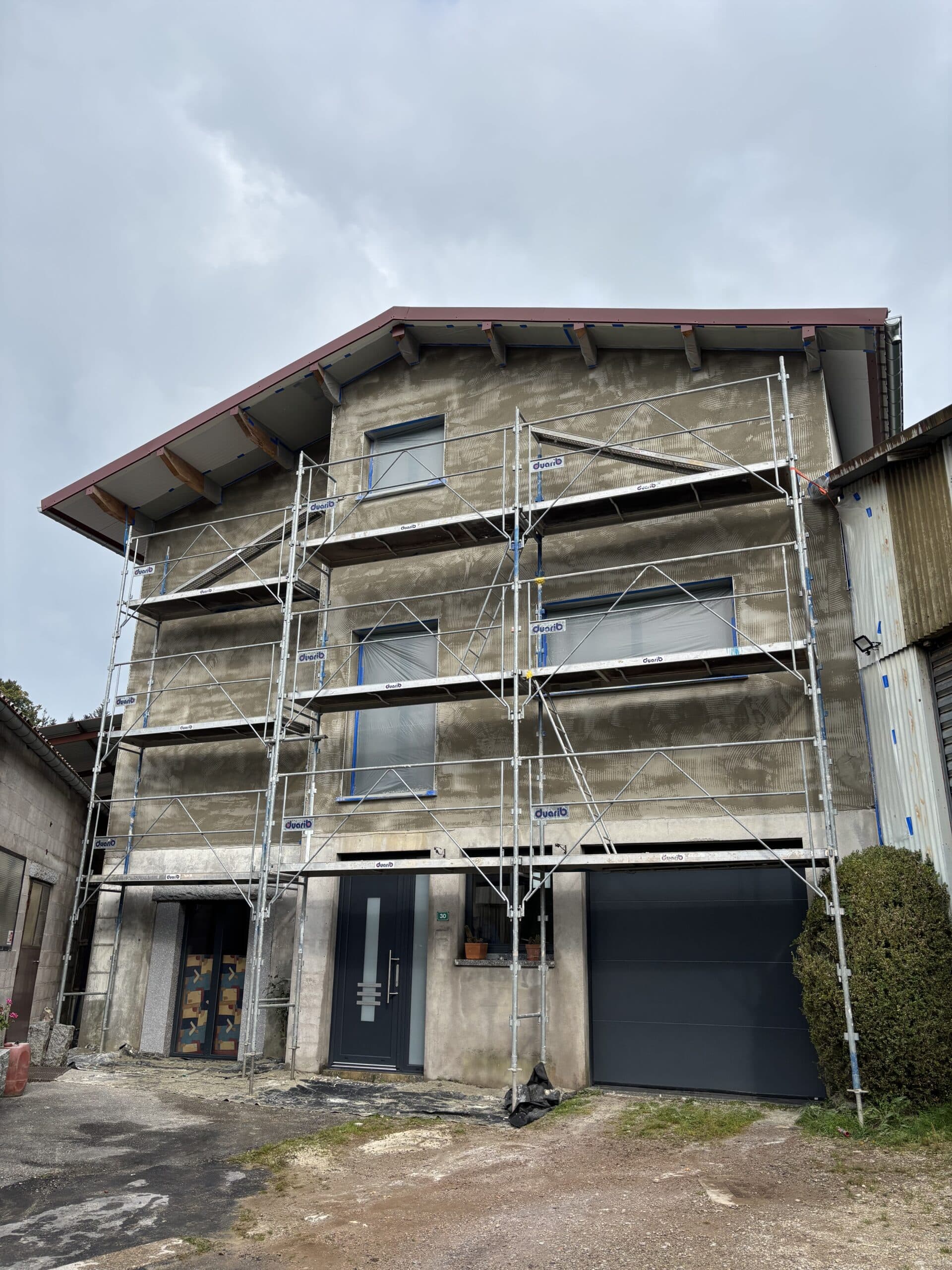 Façade de maison neuve en cours de chantier avec sous-enduit ciment chaux, échafaudage et baguettes de finition – Les Couleurs MS.