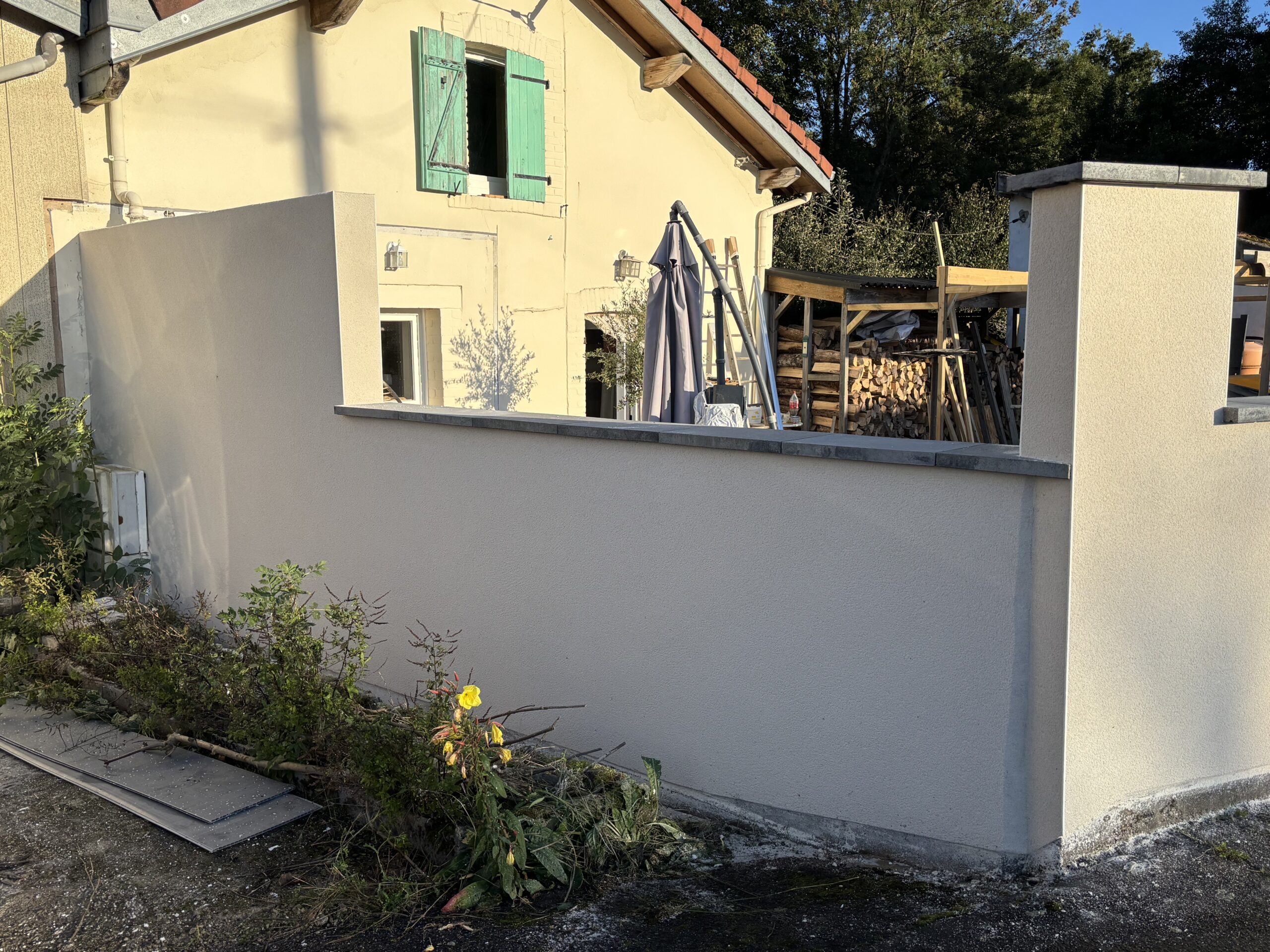 Enduit monocouche Baumit teinte Alger sur murette extérieure à Vincey avec finition grattée et poteaux rénovés.