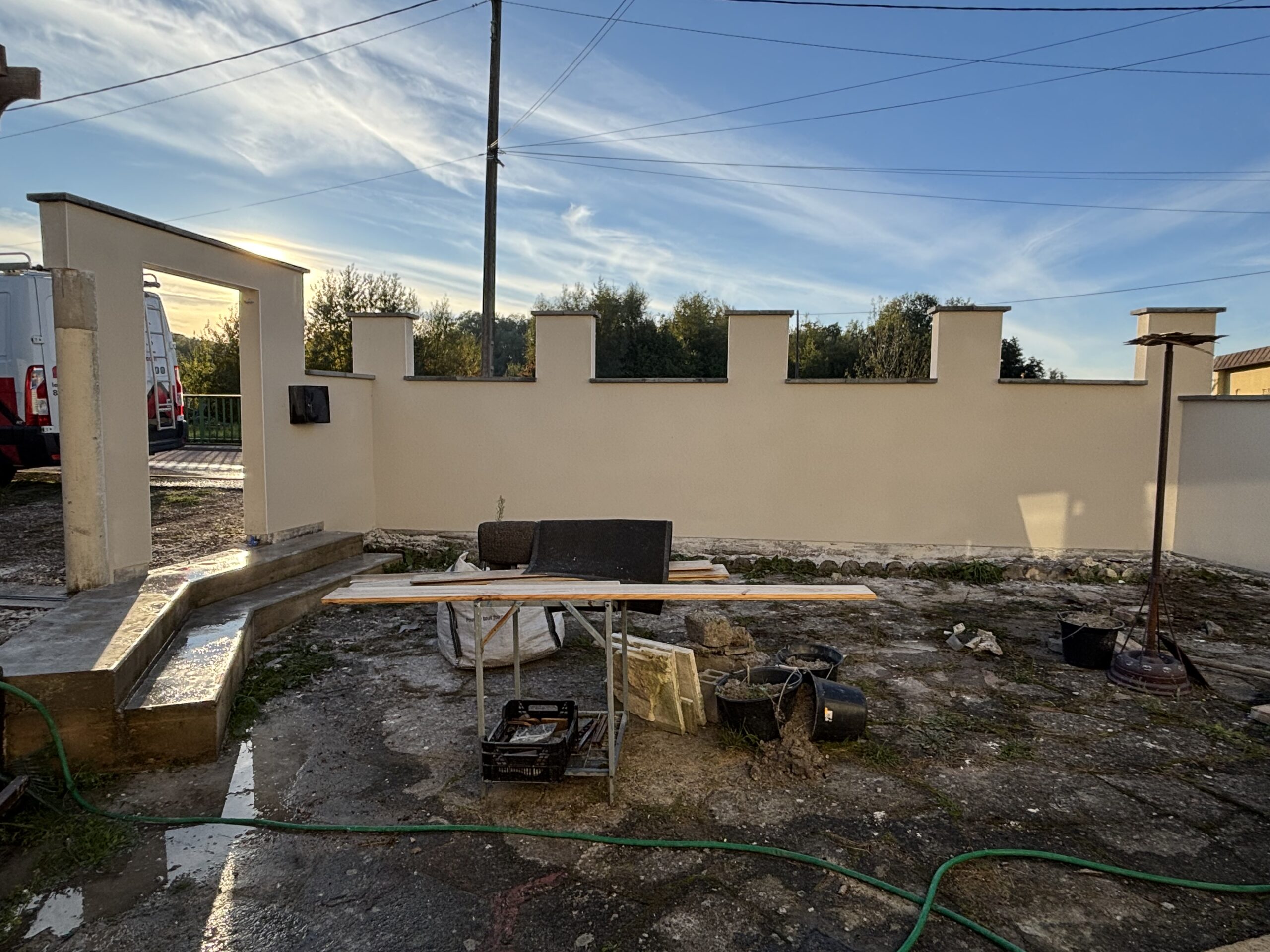 Murette rénovée à Vincey avec enduit monocouche gratté Baumit teinte Alger et finition RPE sur poteaux de portail.