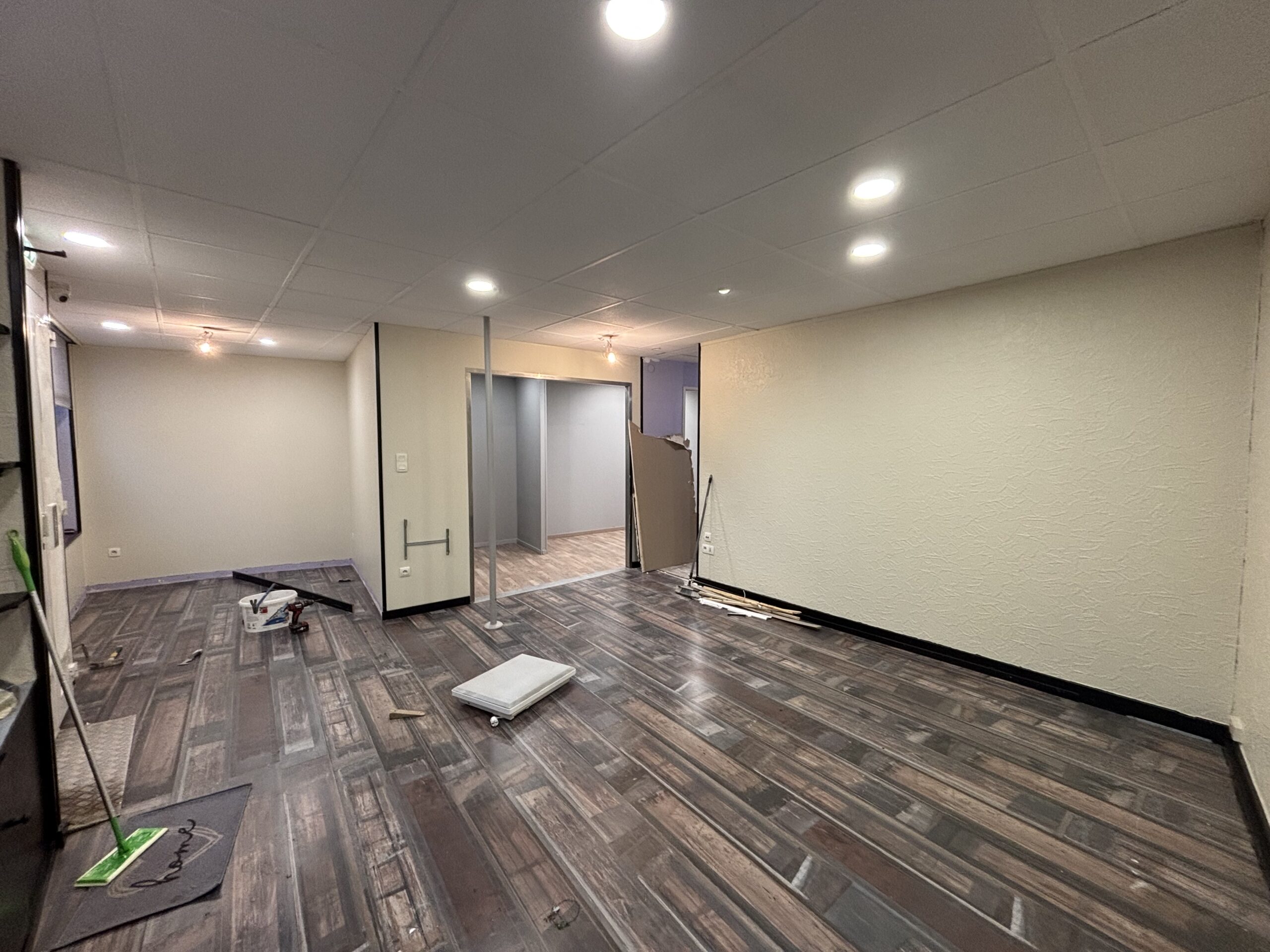 Chantier de rénovation d’un local commercial à Rambervillers comprenant démolition de cloisons, travaux de peinture, installation d’un parquet stratifié et pose d’une porte neuve.
