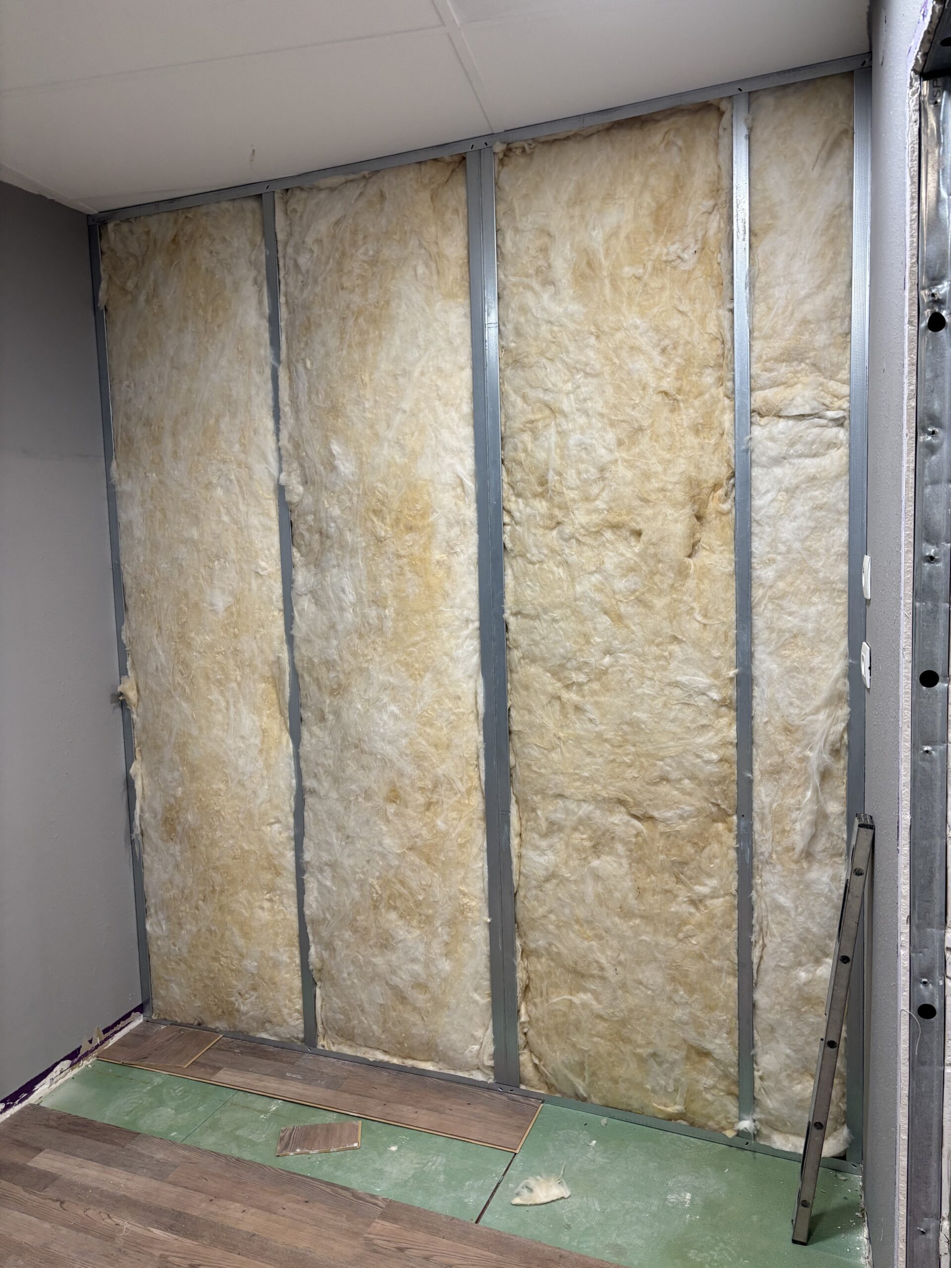 Pose d’une isolation phonique dans une cloison en plaques de plâtre sur ossature métallique lors de travaux de rénovation intérieure.