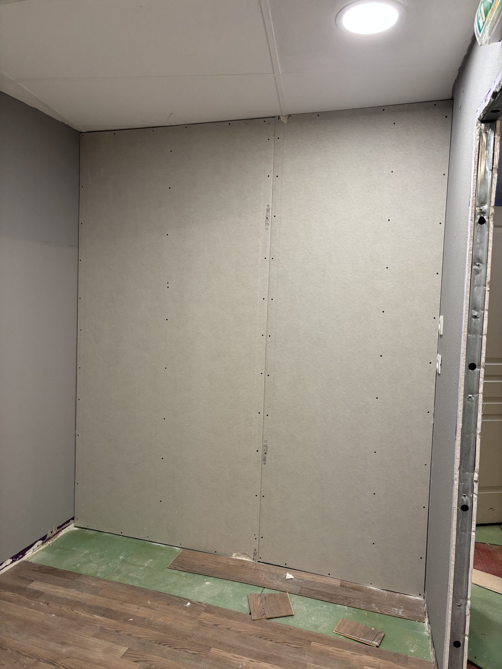 Pose de plaques de plâtre sur ossature métallique lors de travaux de création de cloison intérieure.