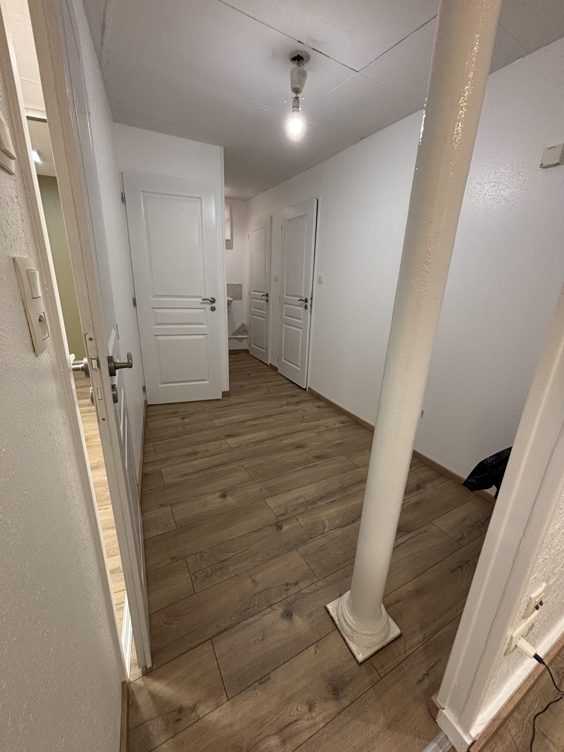 Travaux de peinture des murs et plafonds avec pose d’un parquet flottant dans le cadre d’une rénovation intérieure.