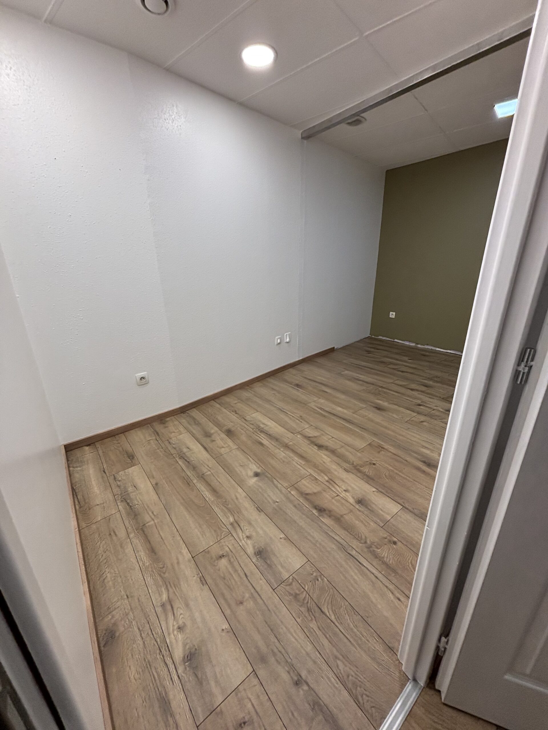 Travaux de peinture des murs et plafonds avec pose d’un parquet flottant dans le cadre d’une rénovation intérieure.