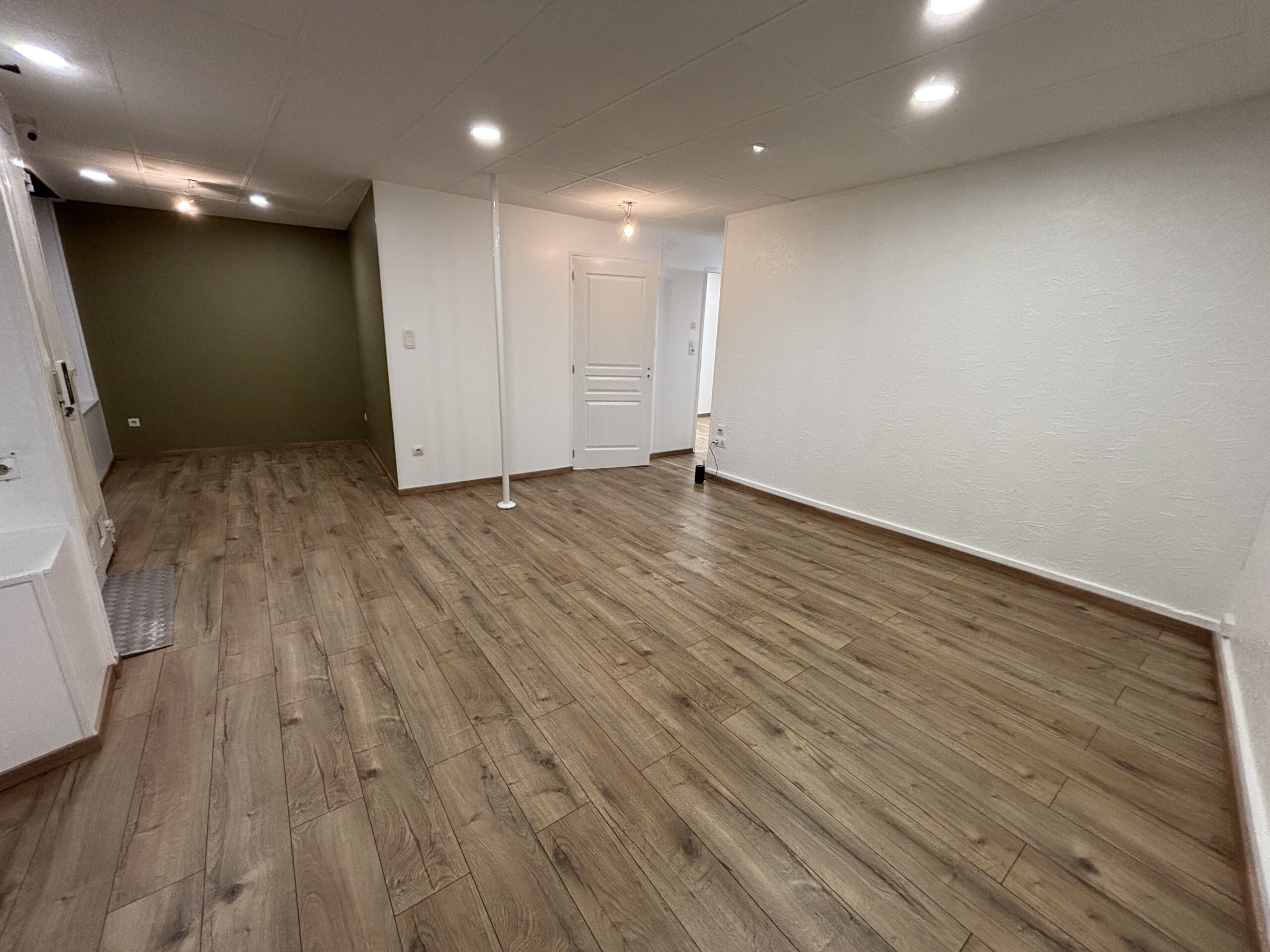 Travaux de peinture des murs et plafonds avec pose d’un parquet flottant dans le cadre d’une rénovation intérieure.