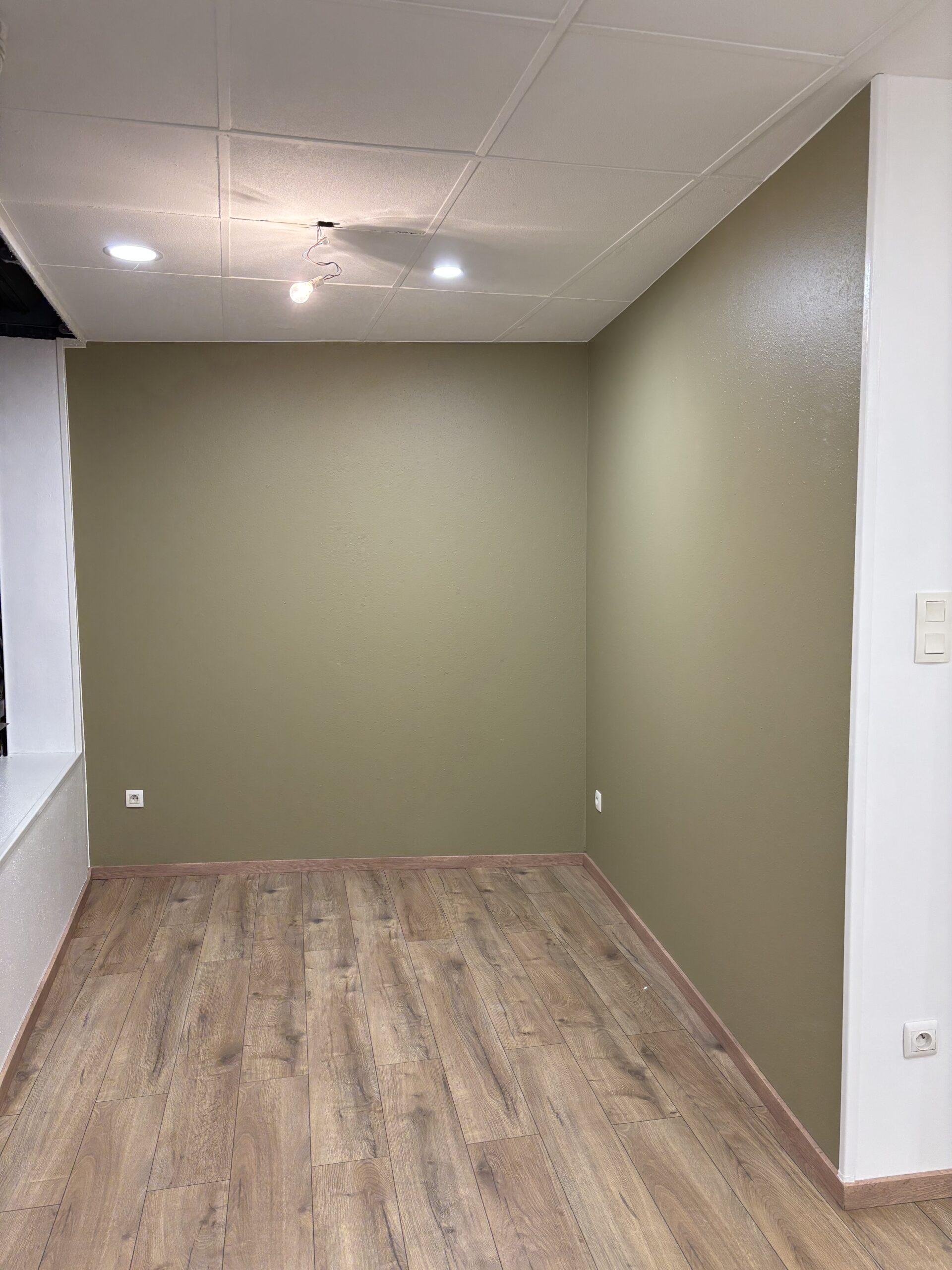 Travaux de peinture des murs et plafonds avec pose d’un parquet flottant dans le cadre d’une rénovation intérieure.